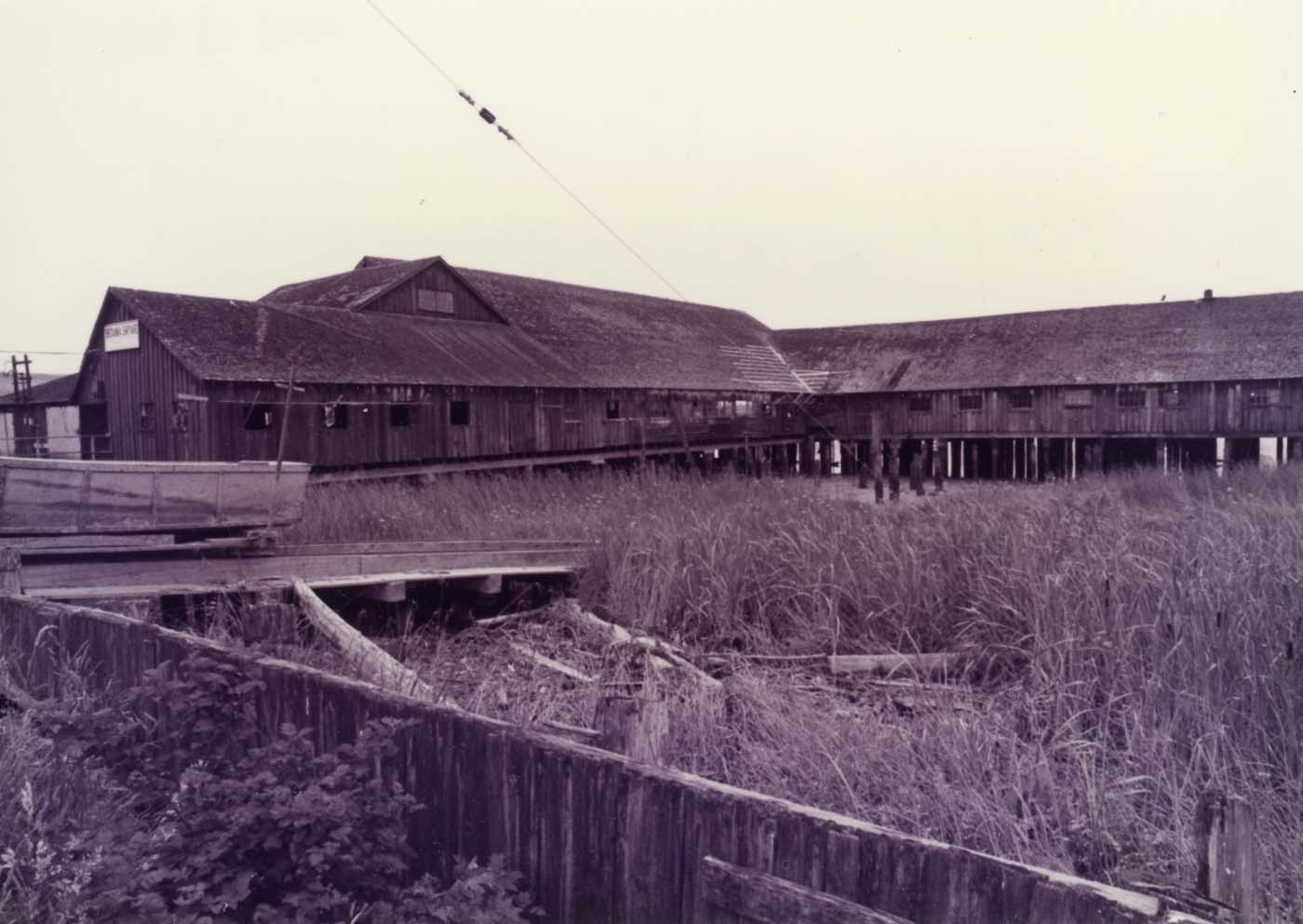 Black and white photo of the Britannia Shipyard building with tidal marsh in foreground