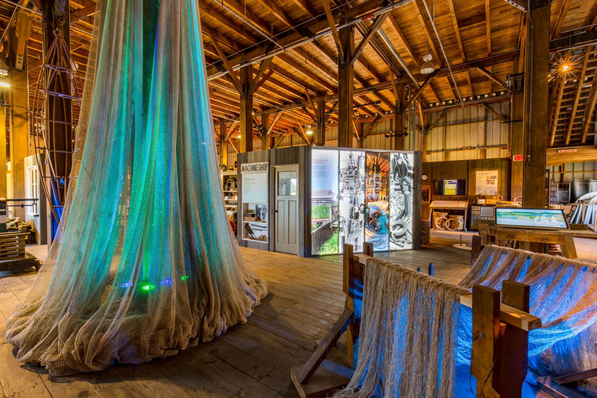 Interior displays of fishing nets illuminated with green and blue lights in the Seine Net Loft