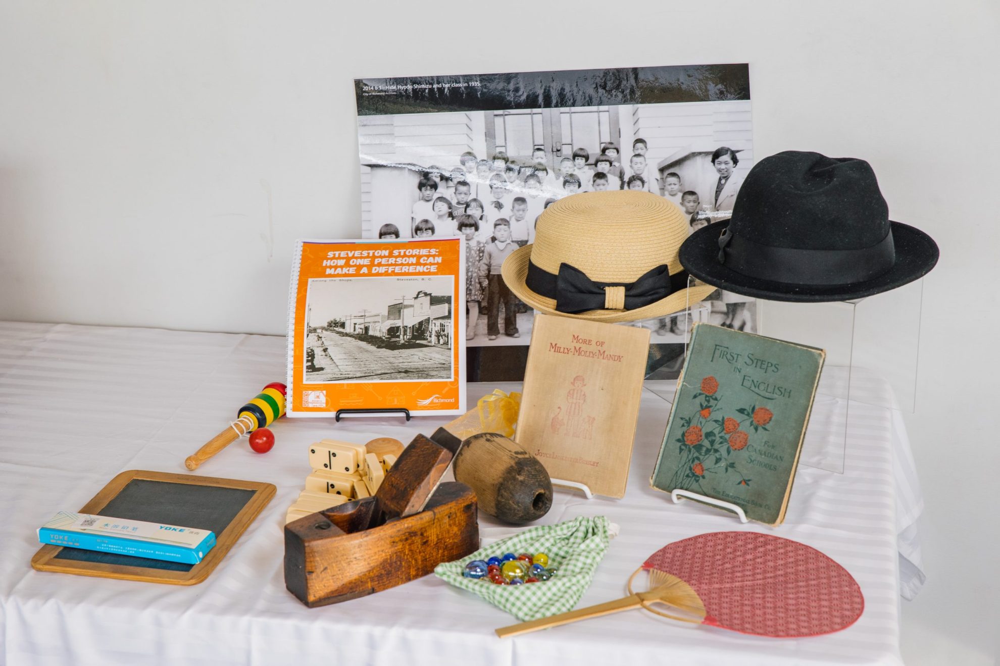 Artefacts and books from the Steveston Stories education kit on display on a white table