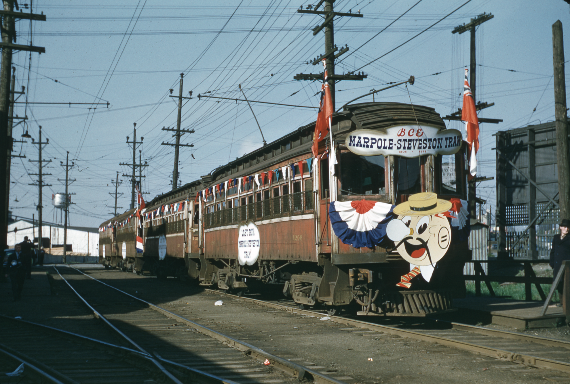 Historic tram decorated with red, blue and white flags and a cartoon illustration of Reddy Kilowatt.
