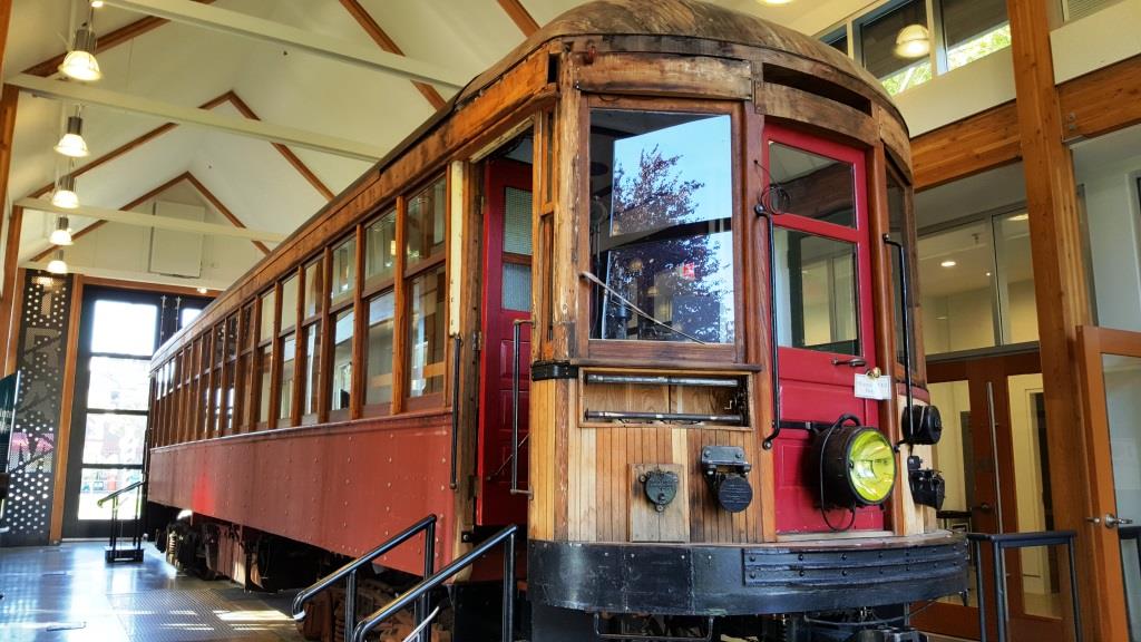 Half restored red historic tramcar with unpainted wood exterior exposed