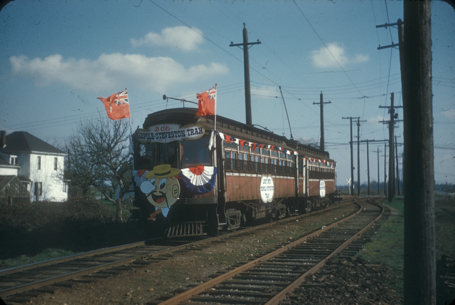 Two-car tram decorate with ribbons on rails under a blue sky with scattered clouds