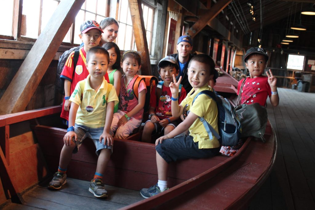 Children sitting inside a red wooden boat