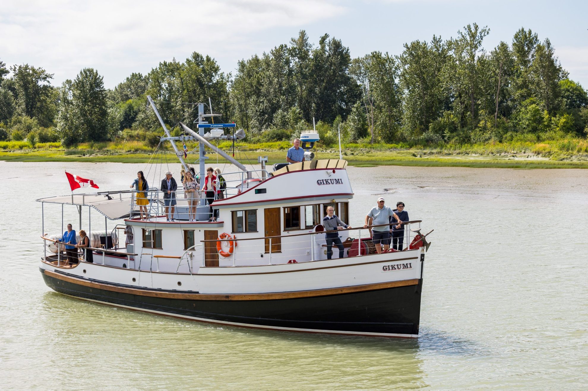 Wooden boat carrying passengers on the green-gray waters of the Fraser River