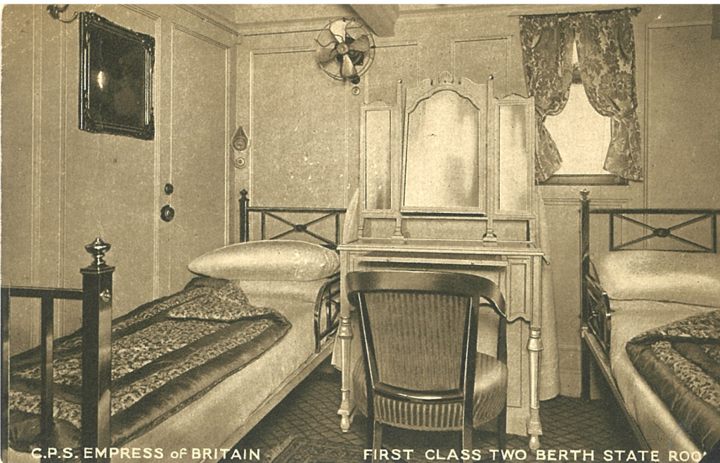 Sepia postcard of showing two antique beds on the side of an ornage desk with table and mirror. 