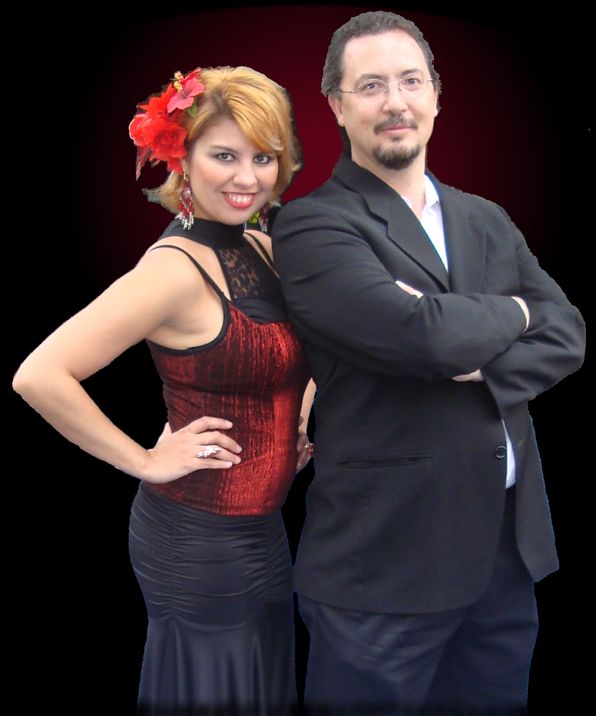 Woman with red flower in hair and red and black dress, standing next to man in dark suit with crossed arms.