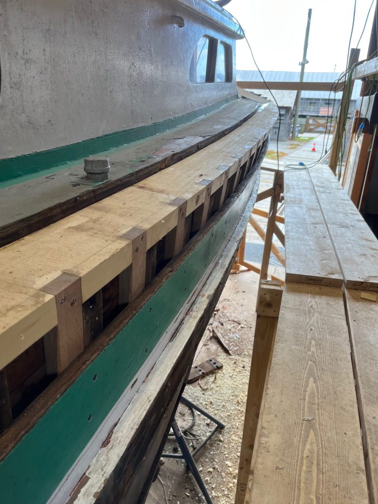 green and white siding of wooden boat along with new timber siding
