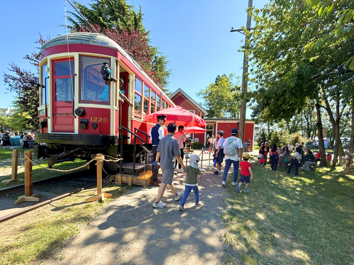 A Steveston Tram attendee welcoming guests onboard Tram Car 1220 outside for Salmon Festival in 2024