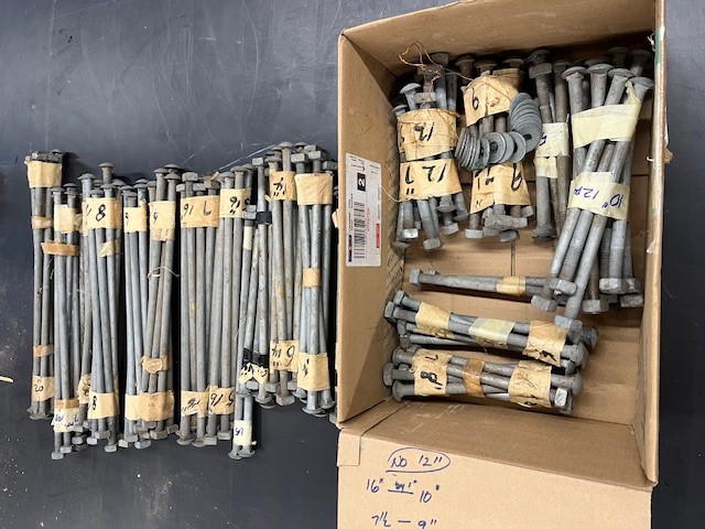Long metal bolts in bundles with numbers and tape, stored in a a box