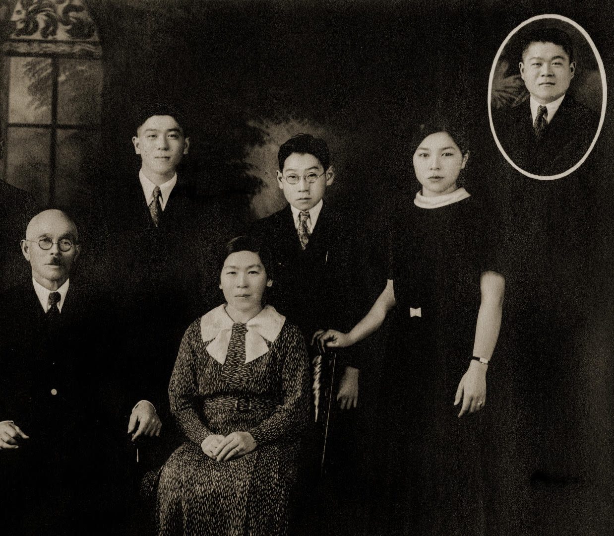 Black and white photo of Japanese Canadian family posing, and an insert of man's photo enclosed in a circle