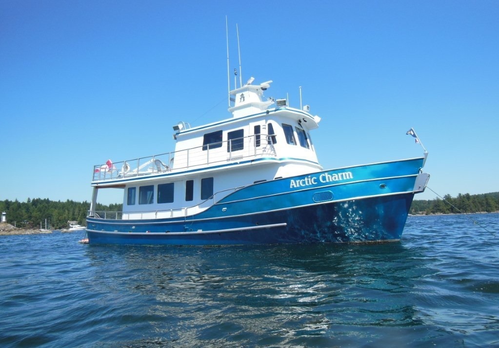 The Arctic Charm (boat with a shiny blue hull) sailing on the water.