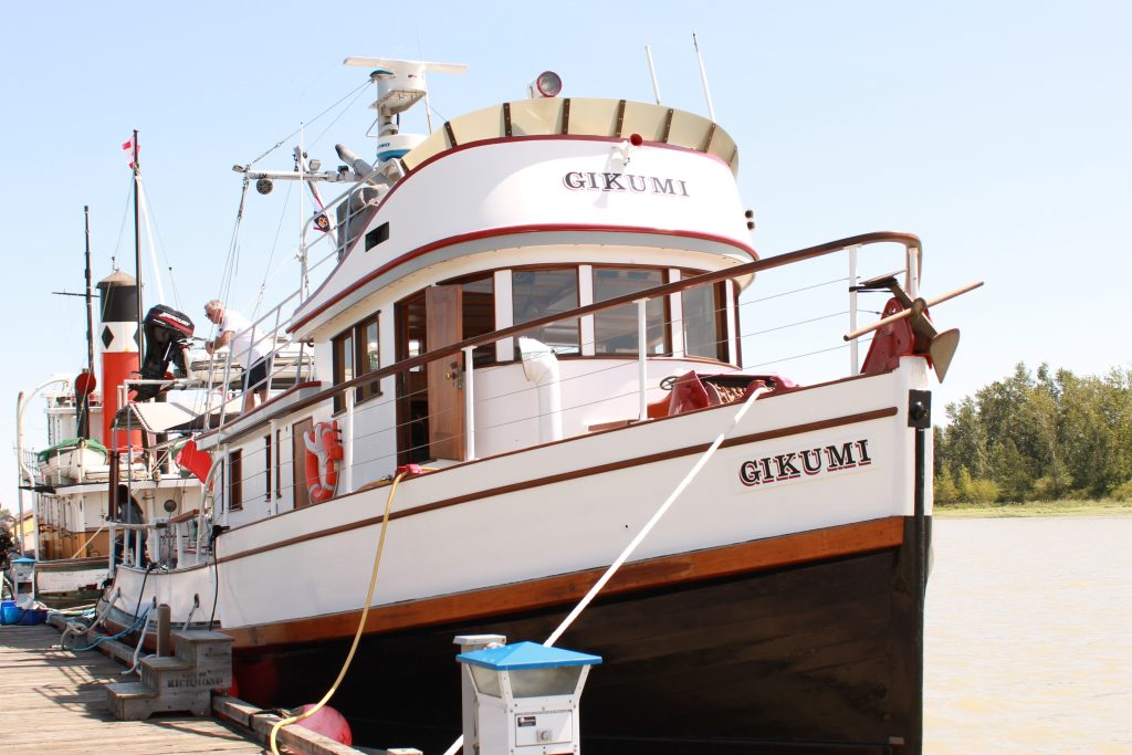 The Gikumi (boat with a white, black, and red hull) docked.