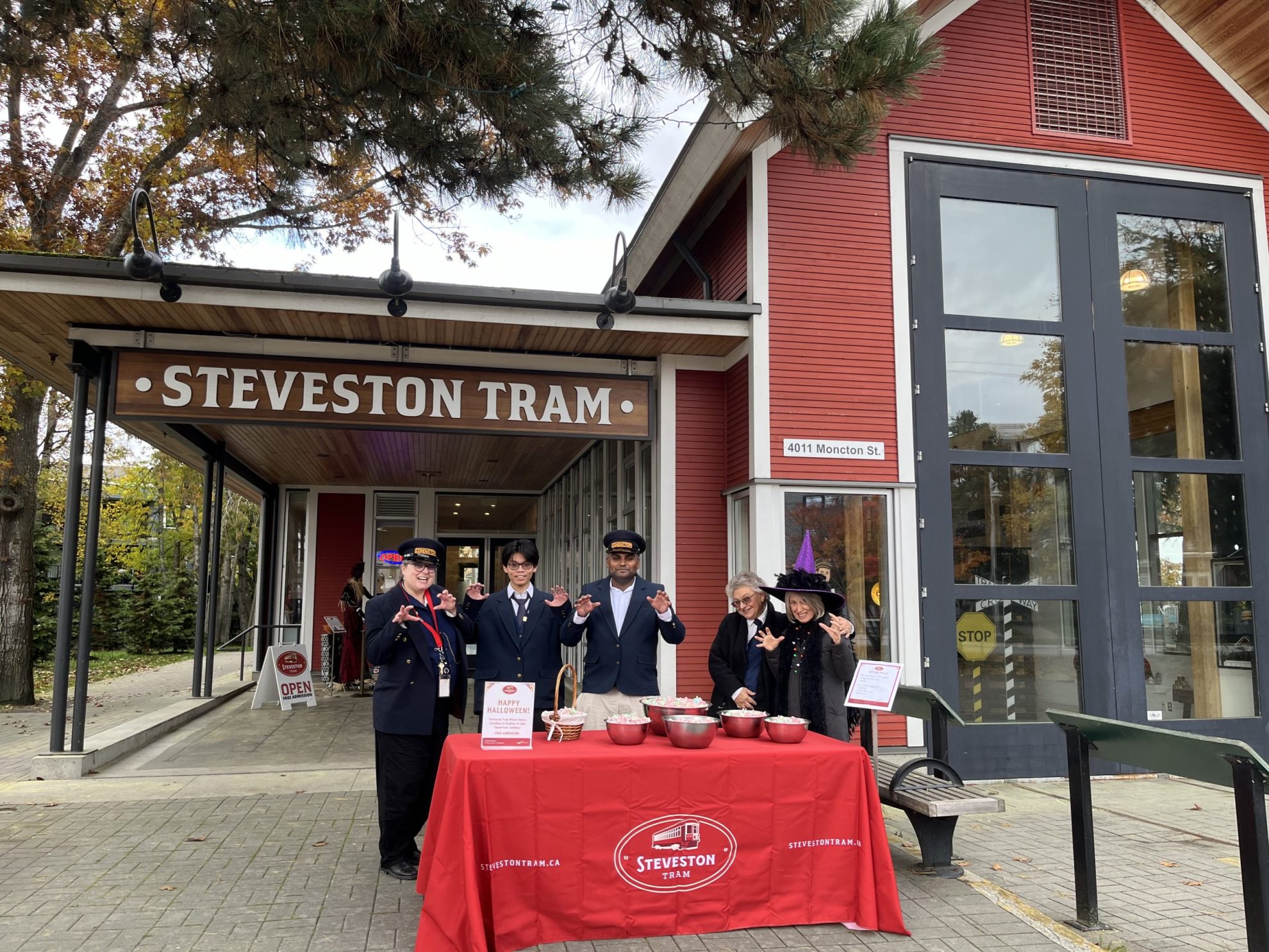 people posing in train conductor costumes in front of Steveston Tram