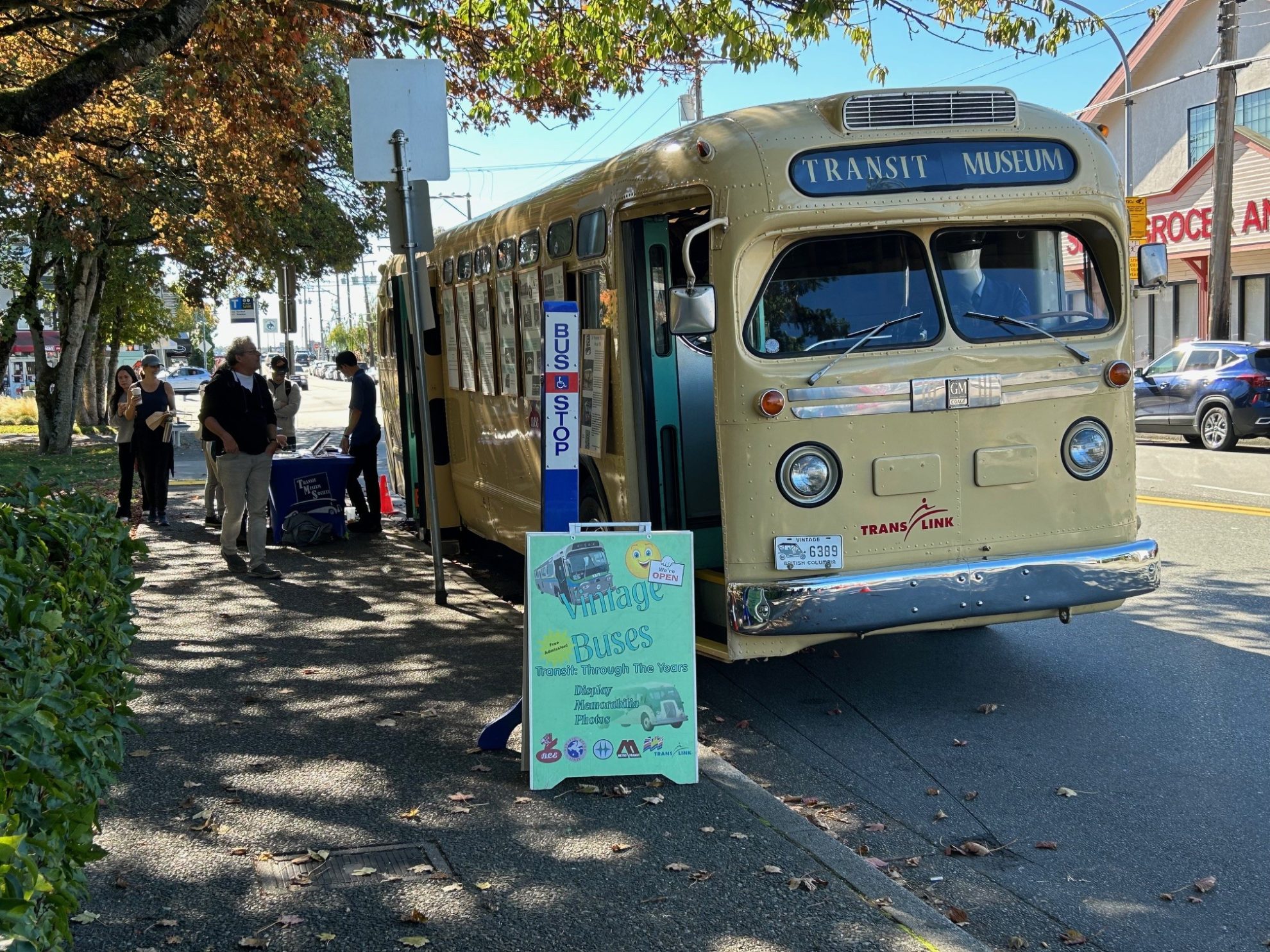 Pale yellow vintage bus parked by old-fashioned bus stop