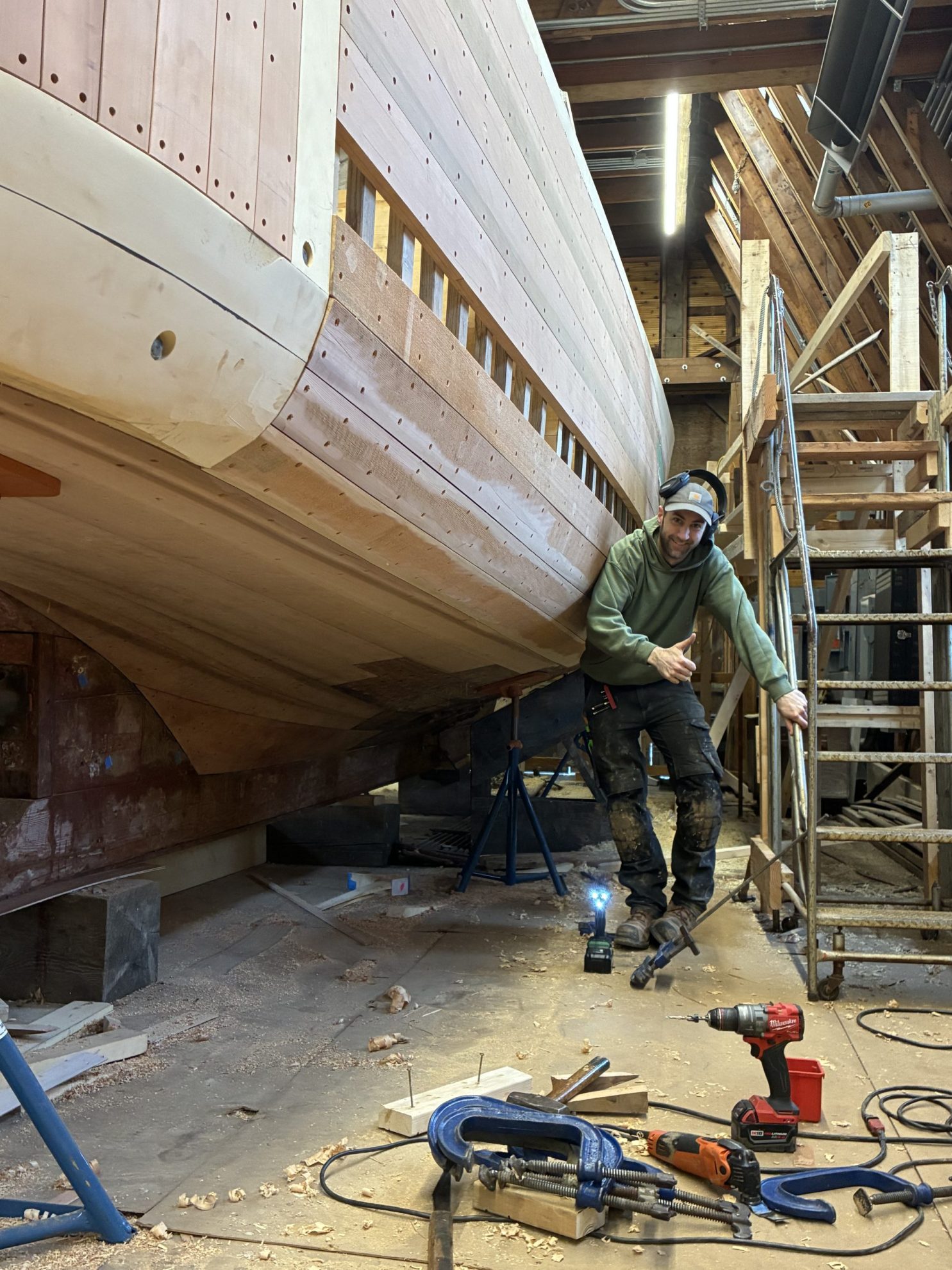 Man standing next to an unfinished wooden boat