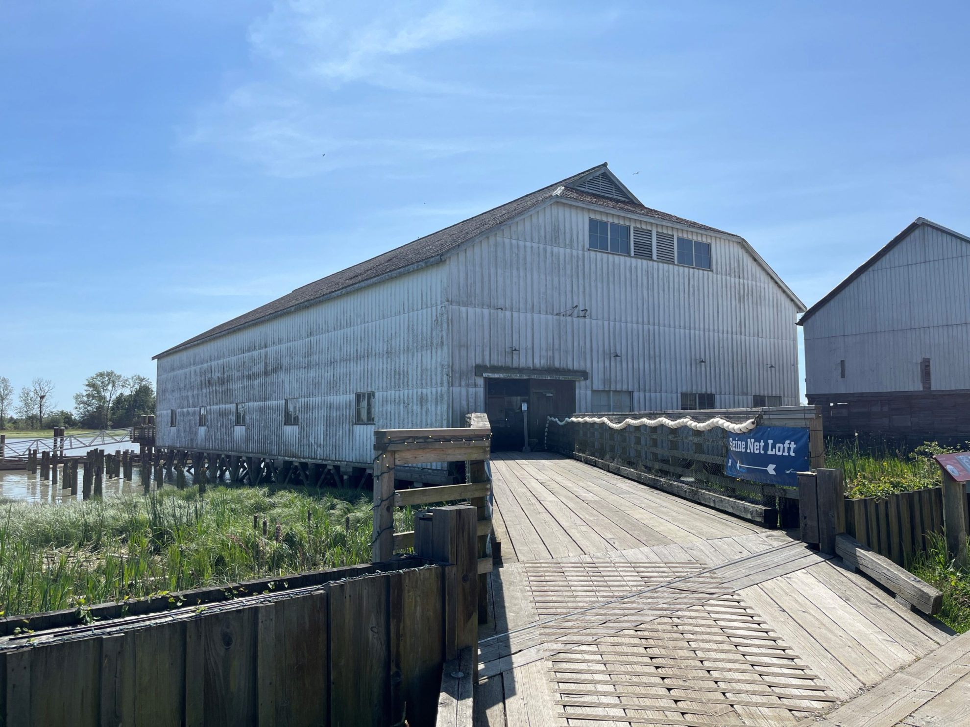Large white wooden building with ramp leading up to entrance under a blue sky