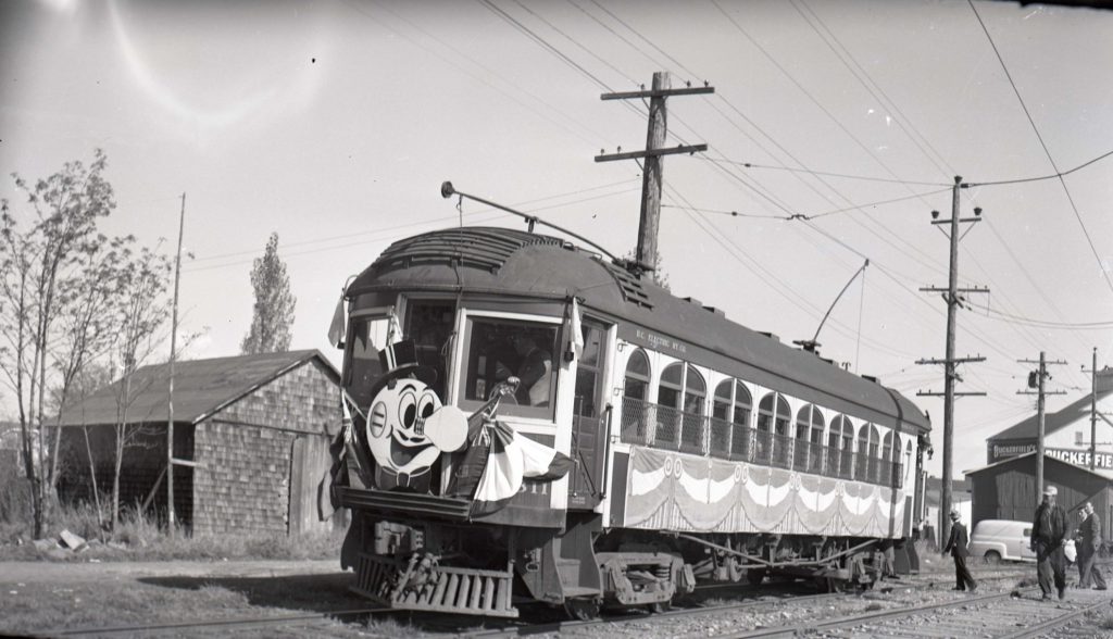 black and white photo of tram with a cartoon character in front.